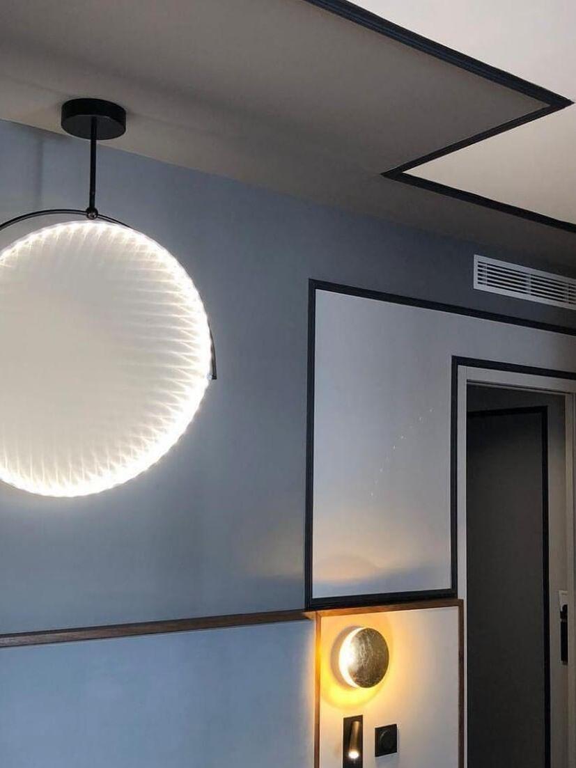 Vertical circular light suspended near a dark wall