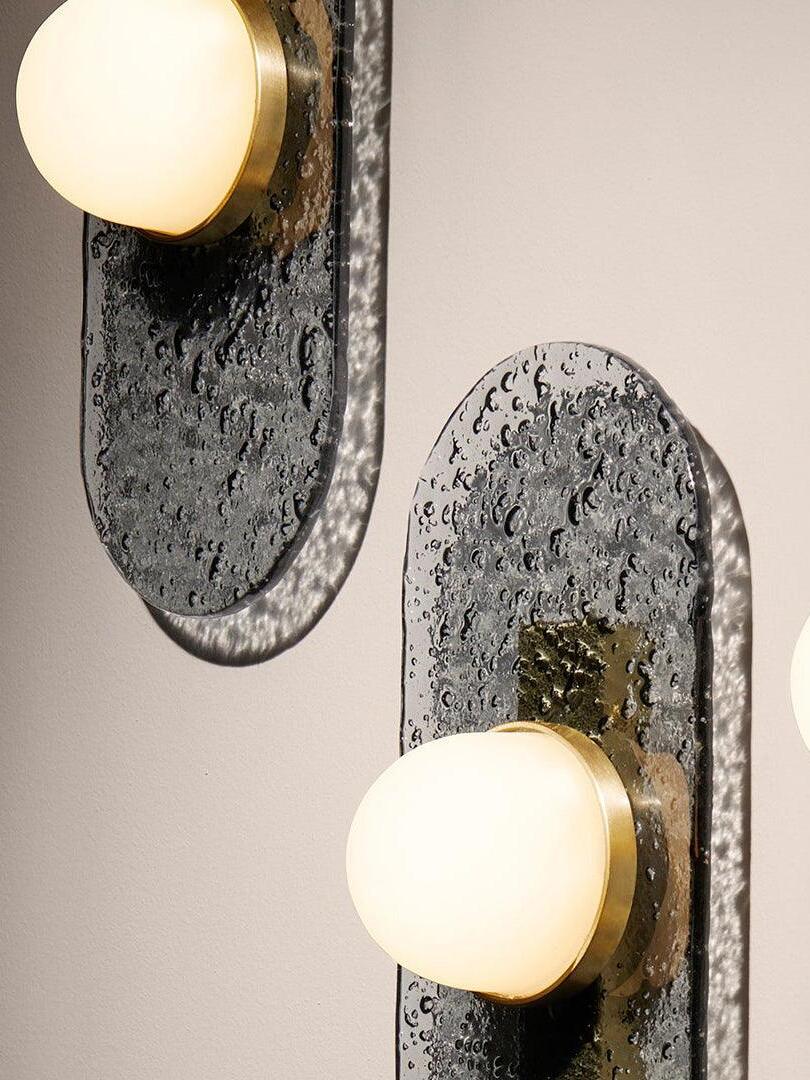 Close view of two separate Modulo panels with textured glass, white domes and gold-tone fittings