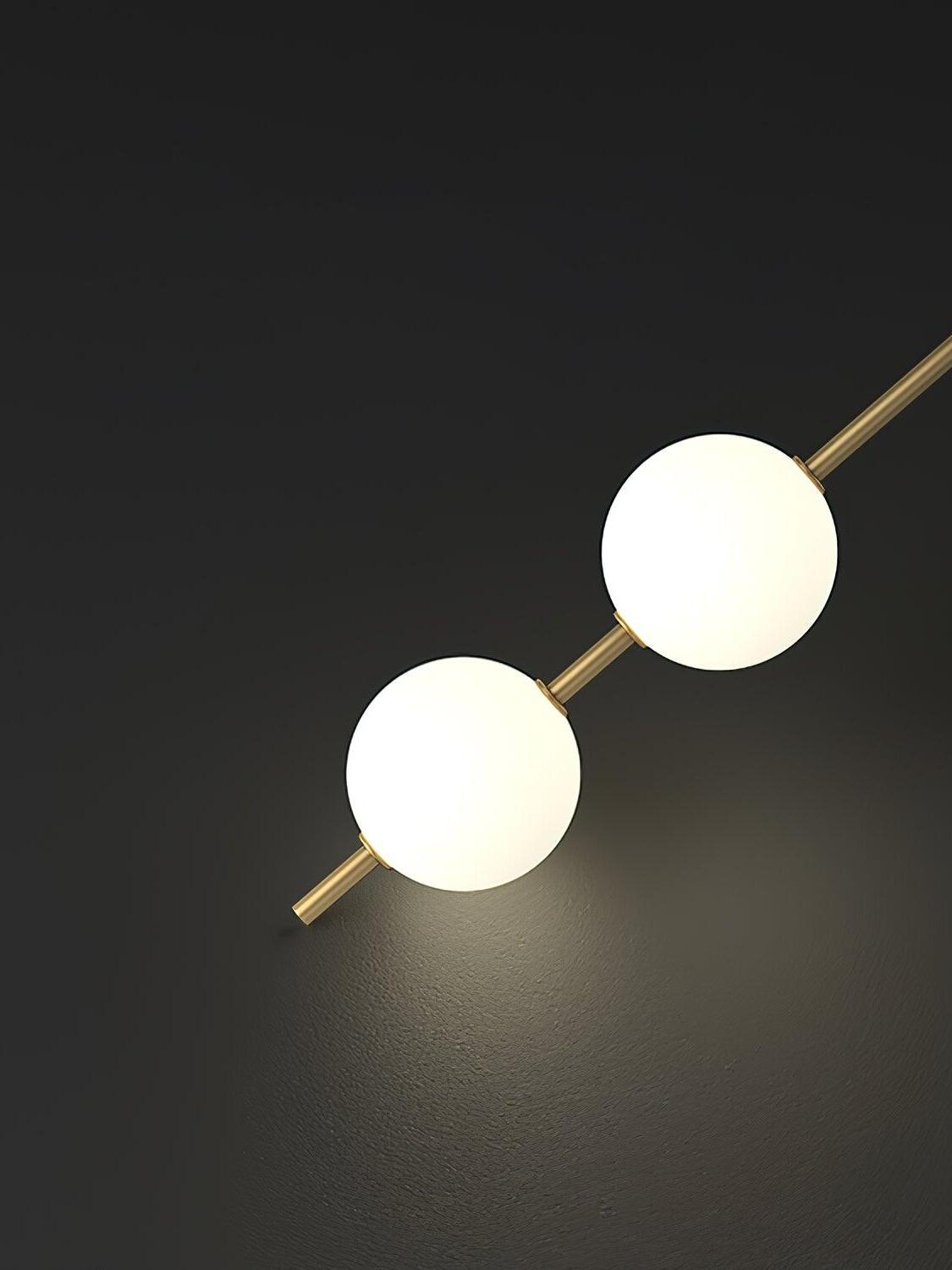 Diagonal close view of two cropped illuminated white globes, gold-colour rod and connecting rings
