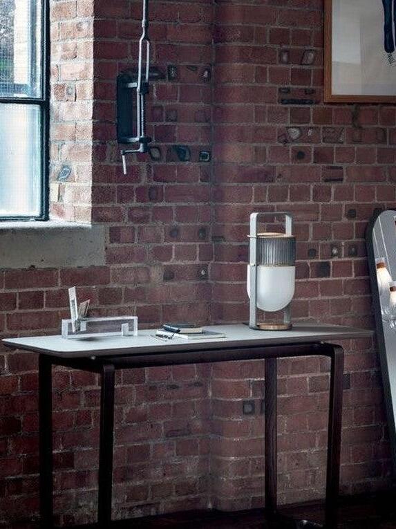 Wide view of a brick-walled workspace with a Xi lamp at the right end of the desk