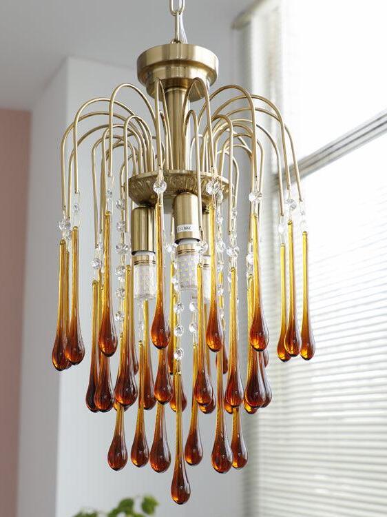 Caramel chandelier viewed beside window blinds