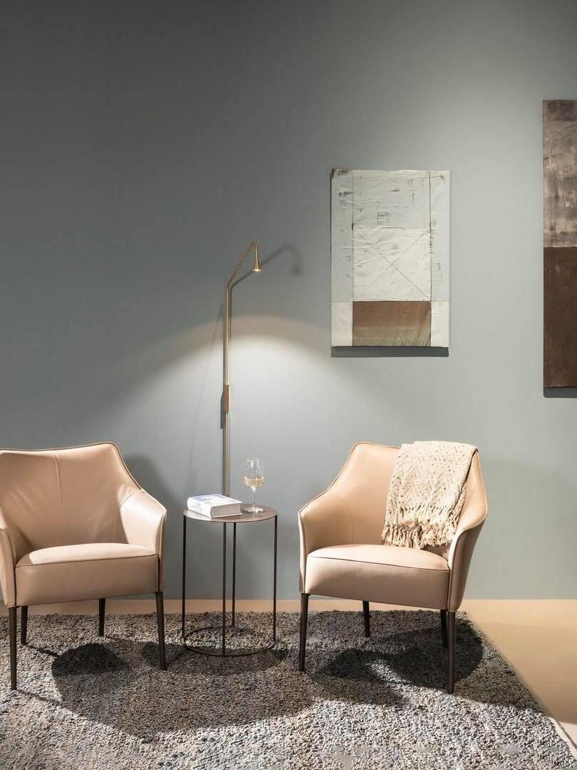 Slender wall sconce above a table between reading chairs