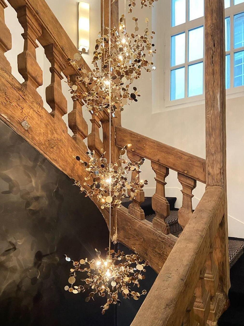 Vertically spaced gold disc clusters beside a wood staircase