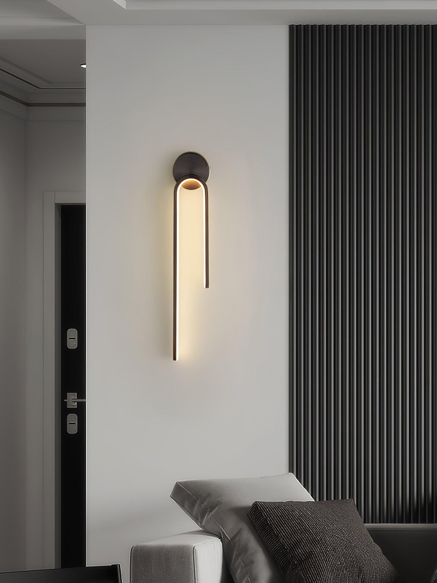 Dark arch with a long left arm above a gray sofa beside vertical wall slats and a doorway