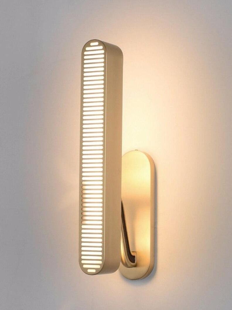 Single lit vertical slotted bar with gold-tone arm, dark inset and rounded backplate against a pale Gray wall