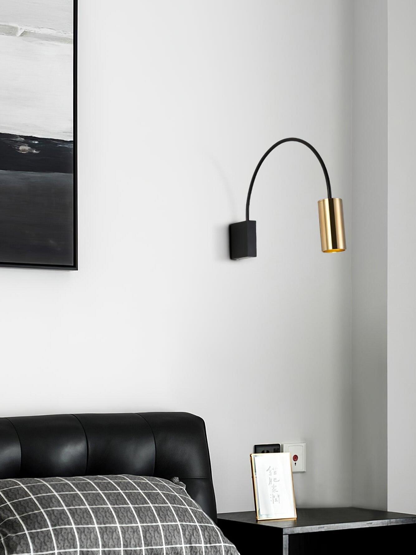 Black-and-gold Antonella light mounted above a dark bed
