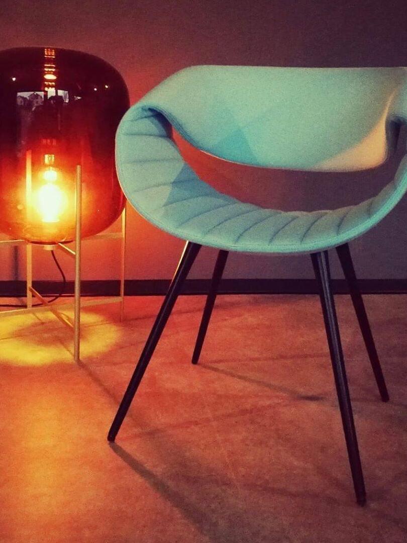 Warmly glowing red-toned glass lamp beside a curved upholstered chair.