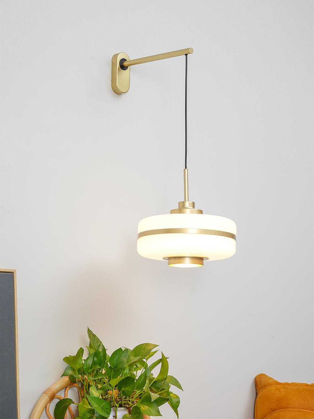 White hanging drum shade above plant and mustard-coloured seat