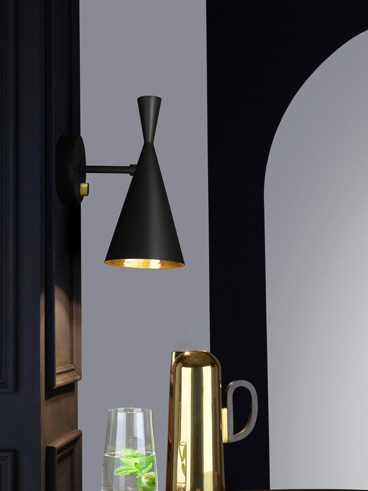 Black conical wall sconce on dark wall near table