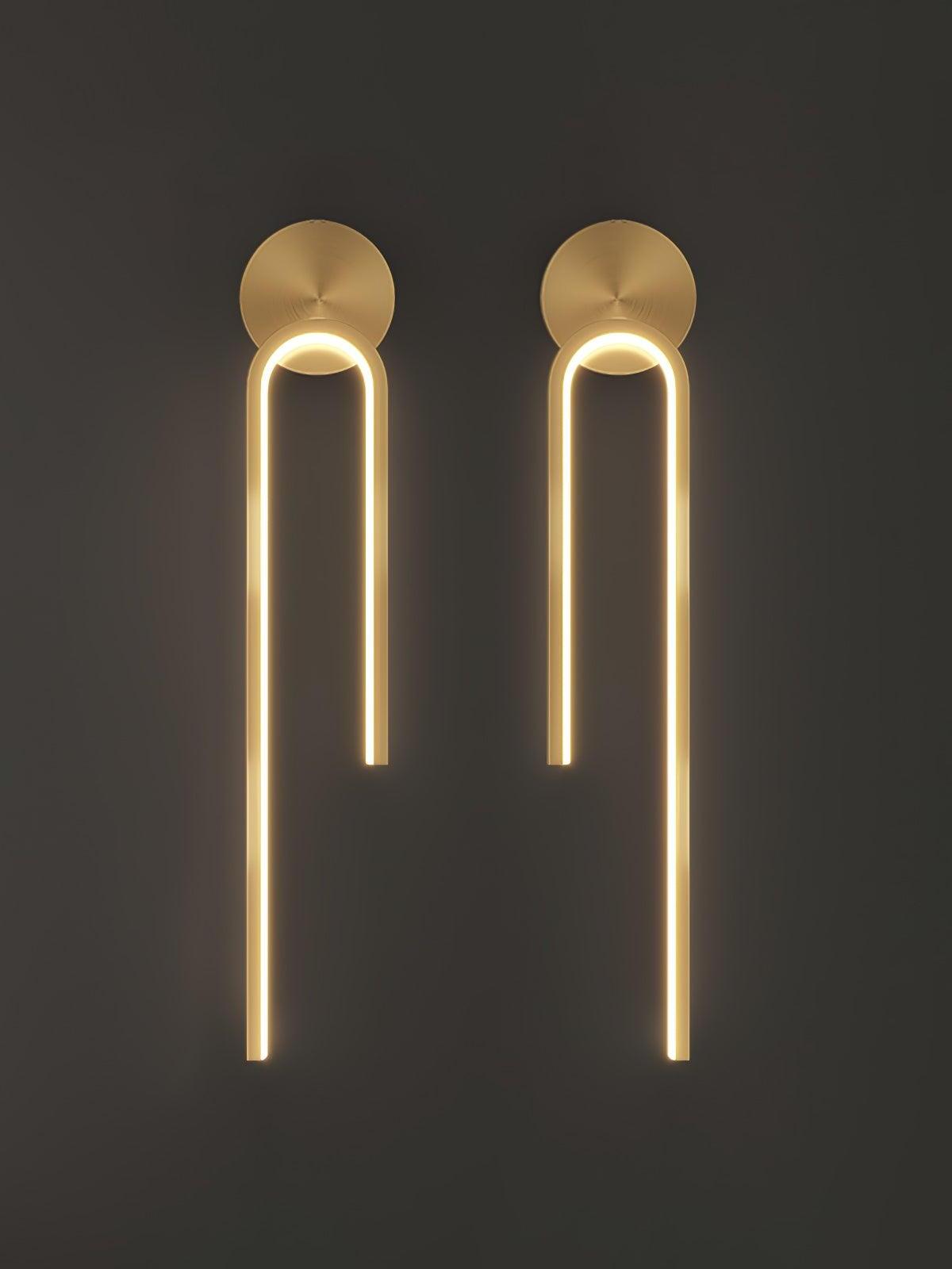 Two glowing gold-tone arch wall lights with mirrored long outer arms and round backplates on dark gray