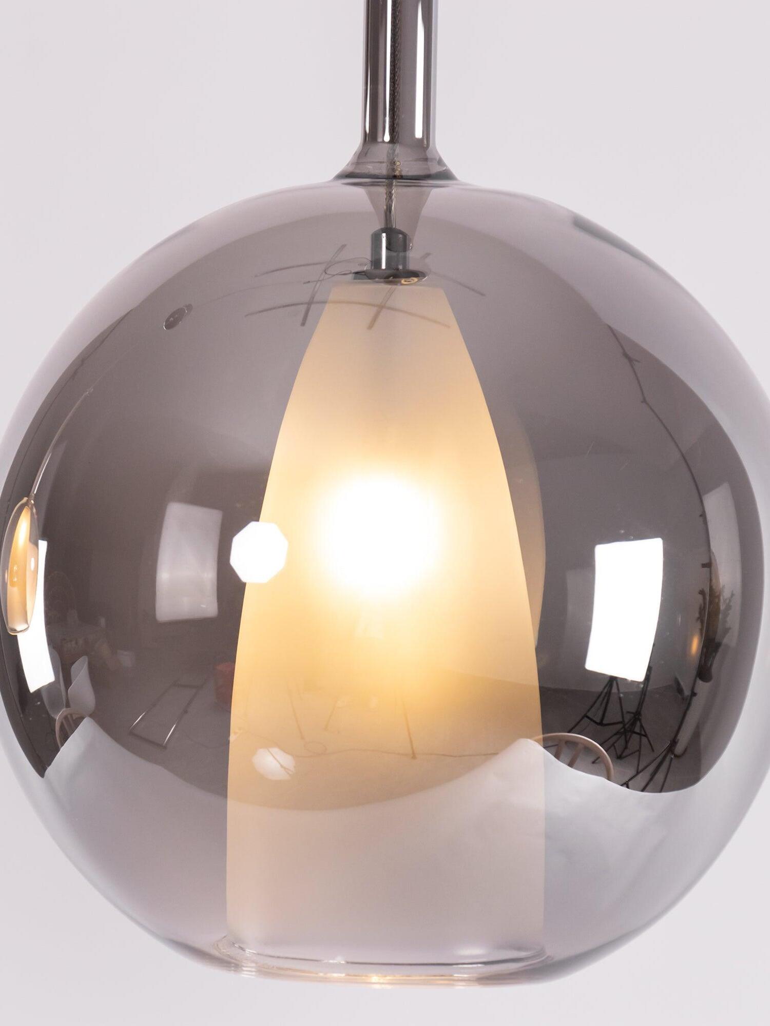 Close view of a reflective dark globe surrounding a glowing white tapered inner shade