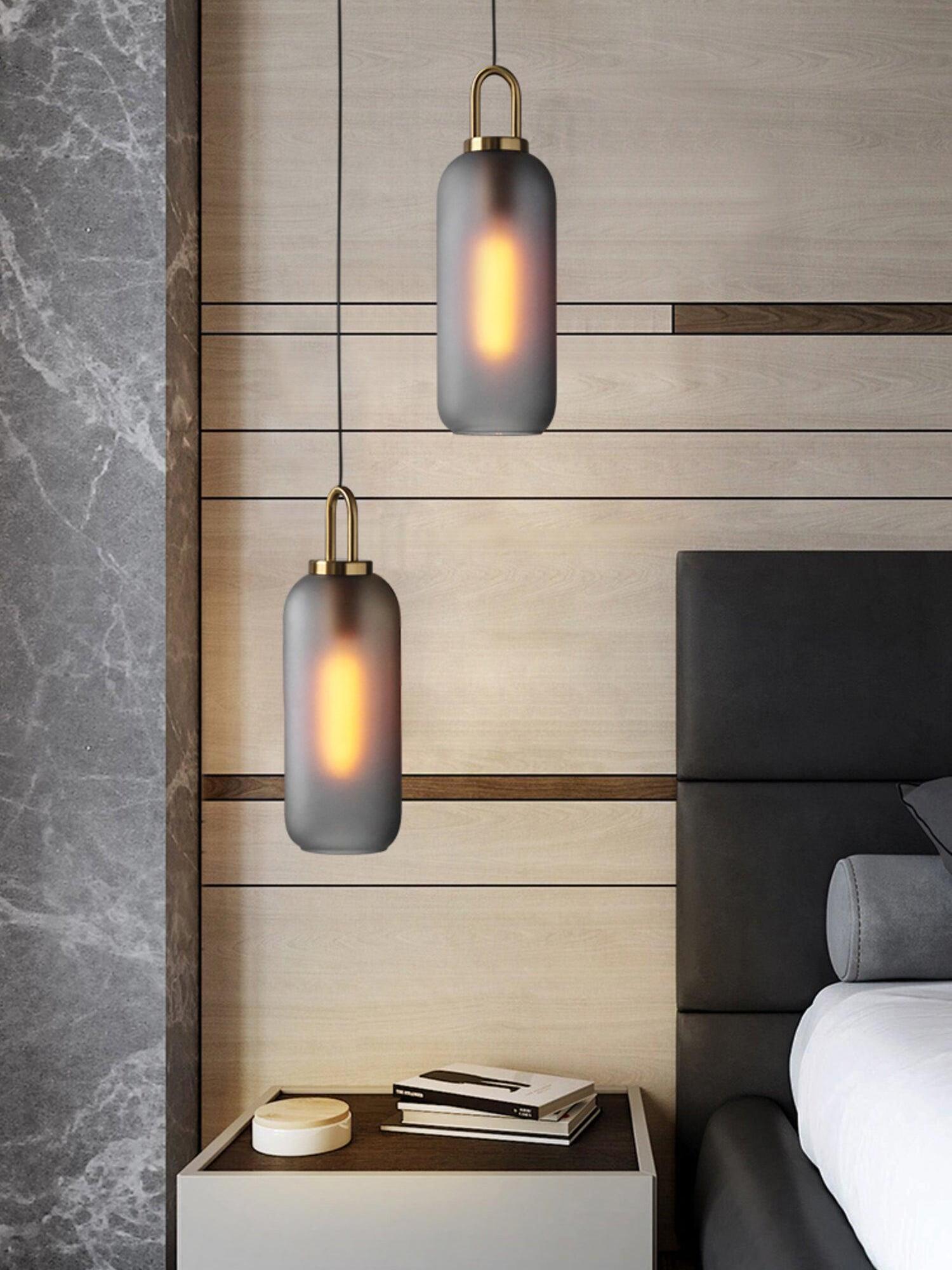 Two frosted capsule pendants beside a bed