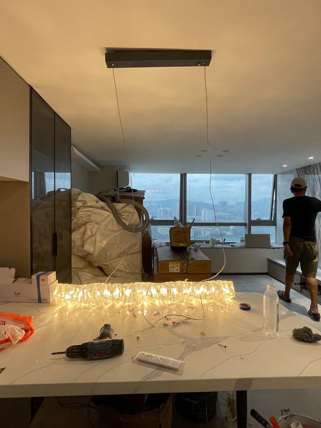 Warm-looking crystal pendant hanging low over tools and packaging in a room under preparation