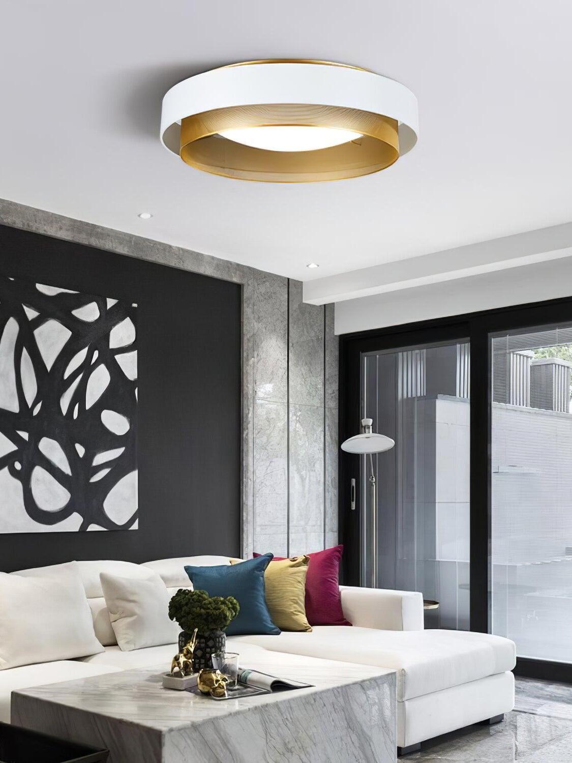 White and gold Nolan ceiling light above a white sectional sofa and dark wall artwork