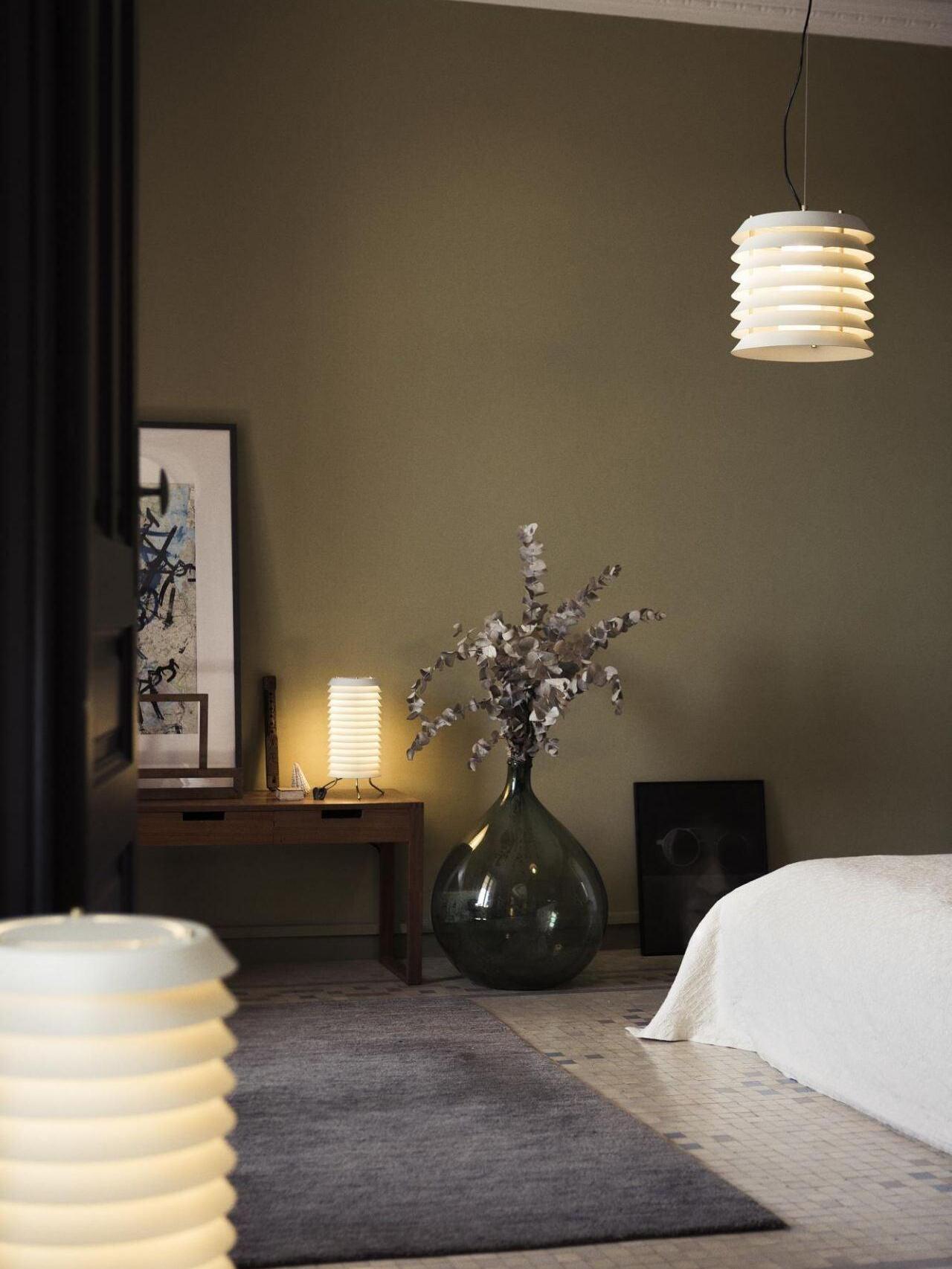 Small lit pendant beside bed with cropped glowing layered object in foreground