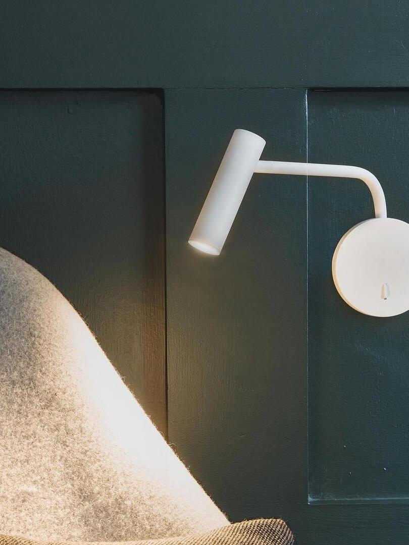 Close view of white wall reading arm beside a chair
