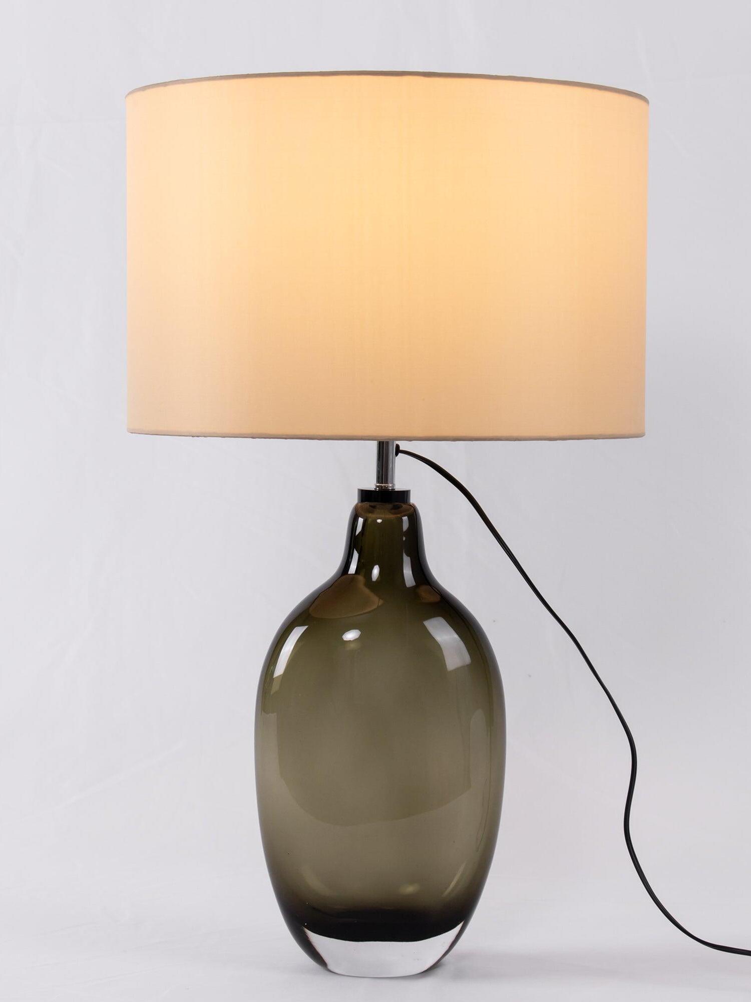 Lit fabric drum shade and black cord near lamp neck