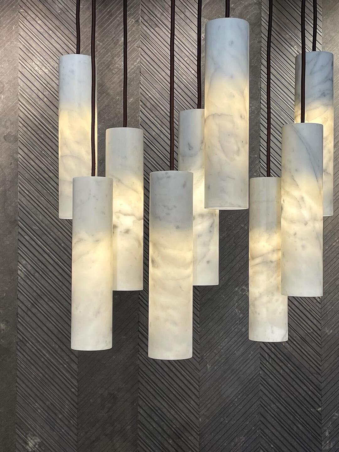 Close-up of glowing veined Silo cylinders hanging at varied heights on dark cords