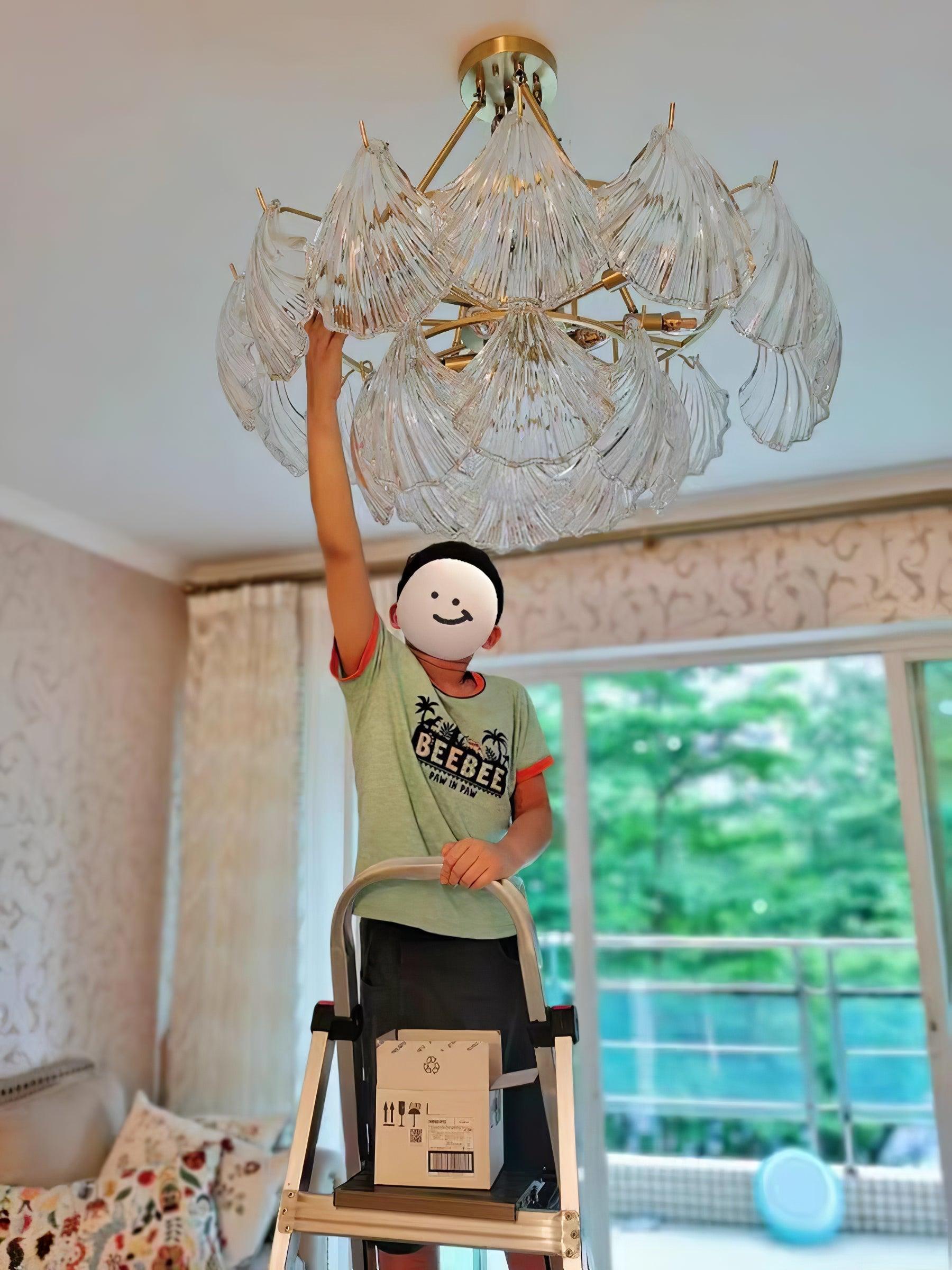 Person beneath an unlit ribbed glass fixture beside a large window