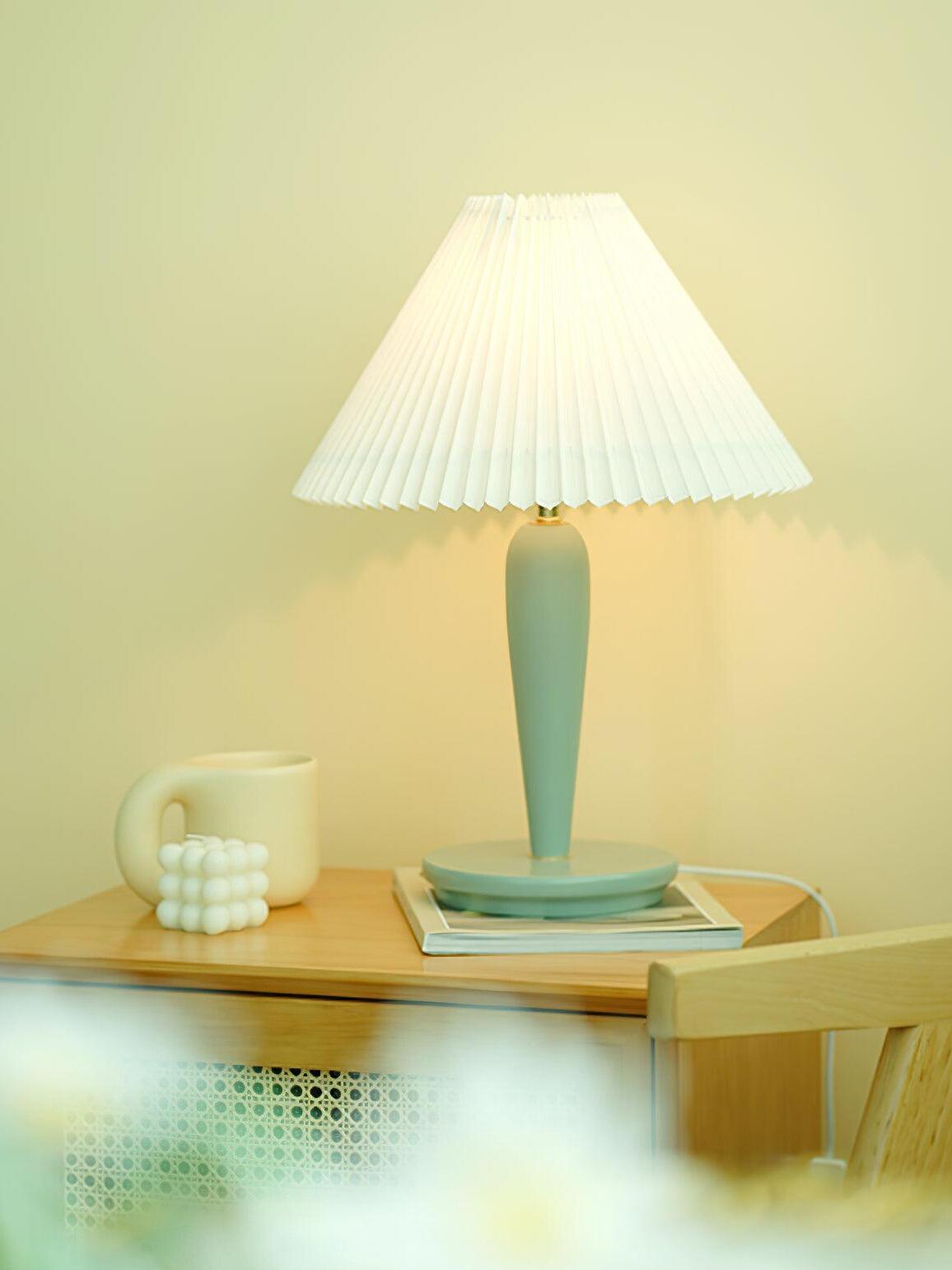 Light-blue lamp with plain pleated shade on bedside table