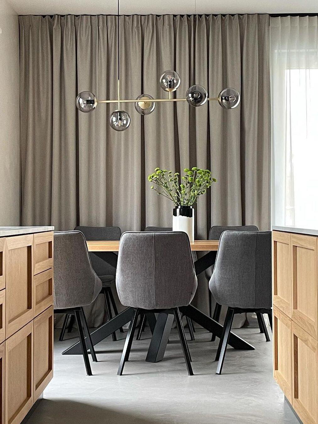 Linear globe chandelier beside dining-room curtains