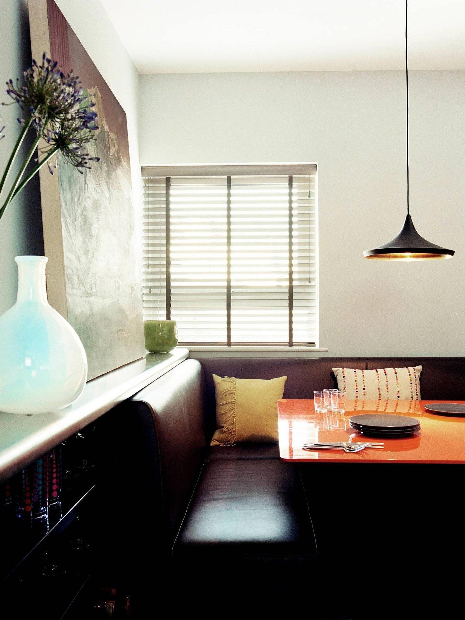 Wide black pendant above a window-side dining nook
