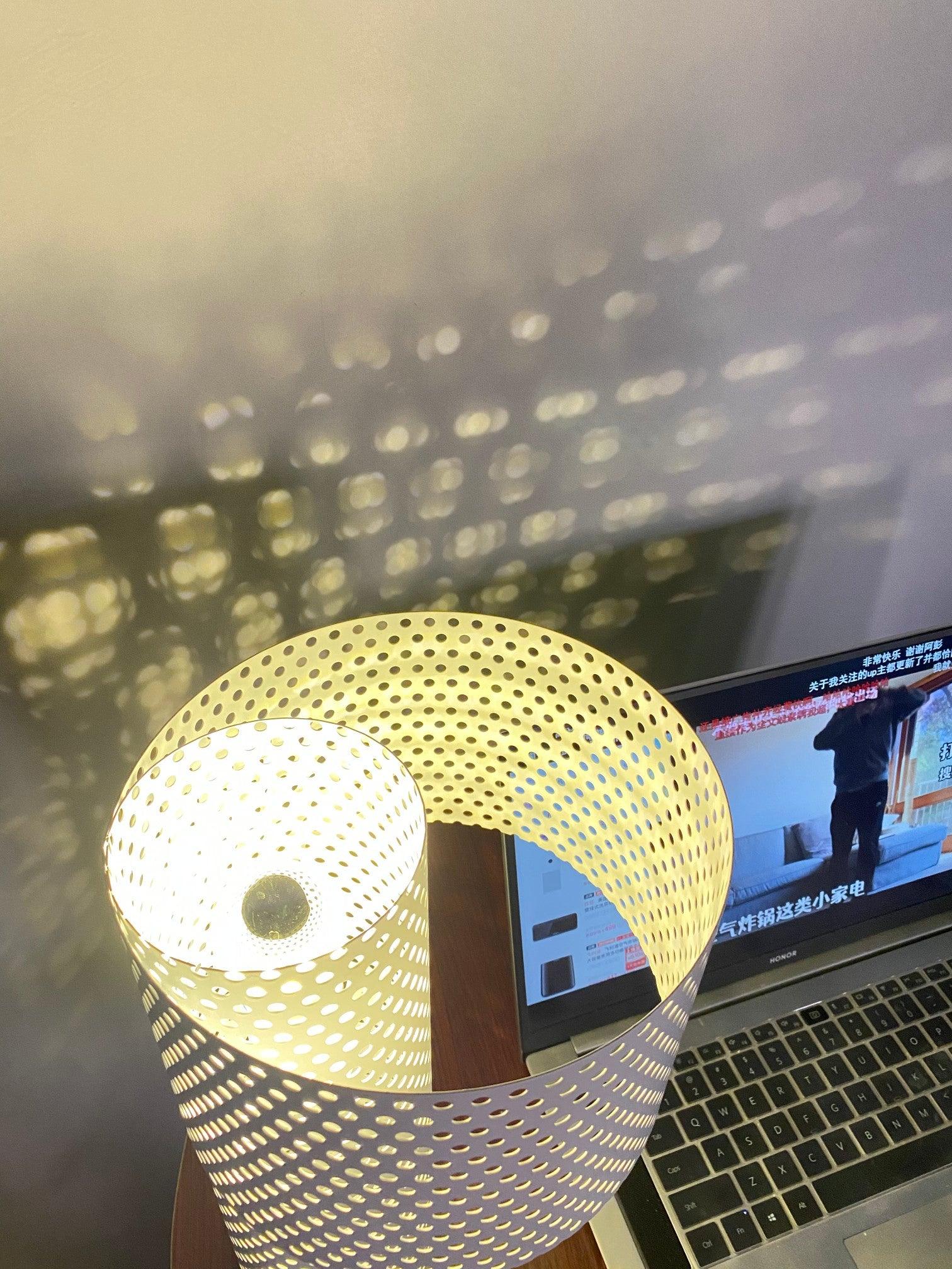 View into lit perforated shade with bulb and wall pattern