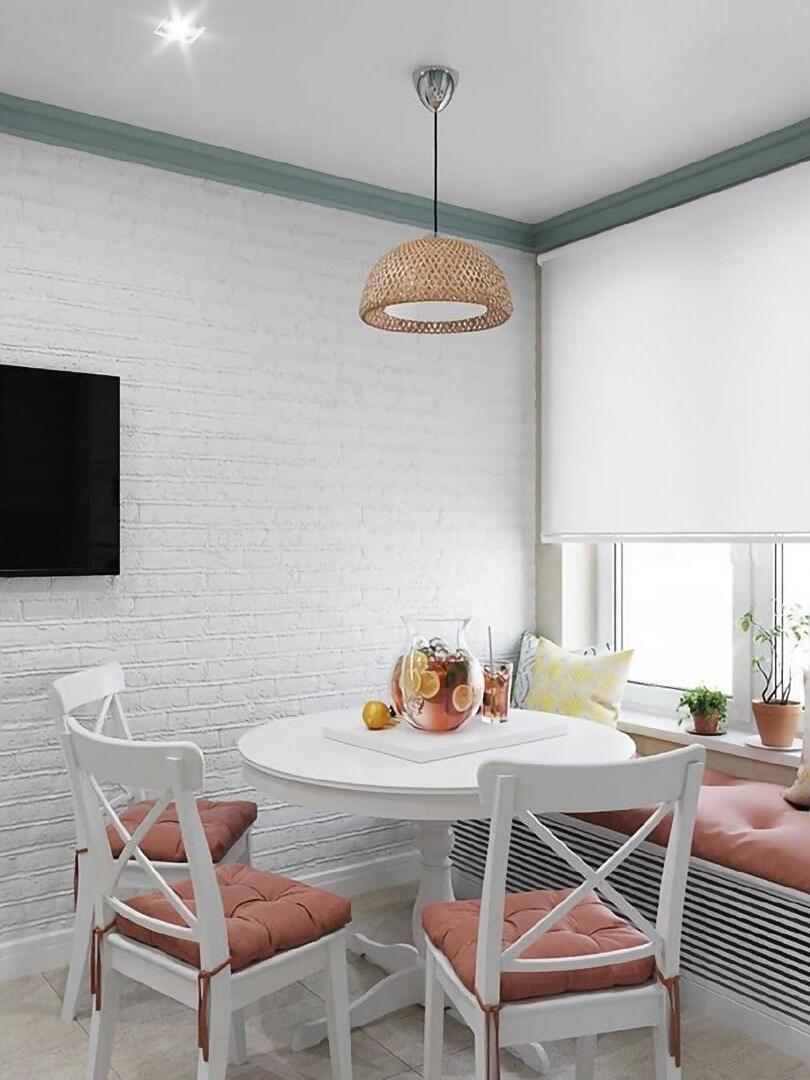 Woven dome light above dining table by white brick wall