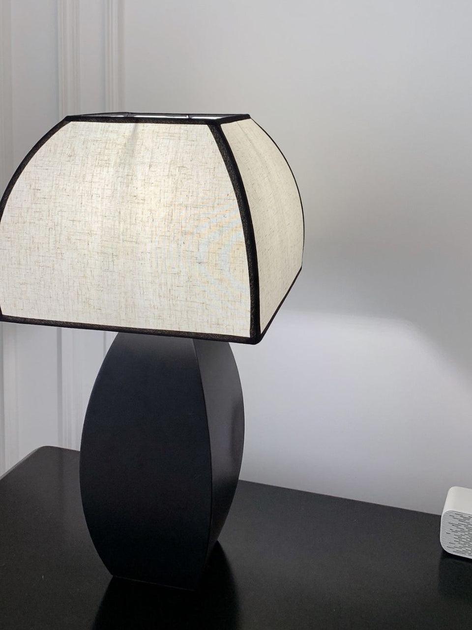 Close view of pale shade with black piping over dark base