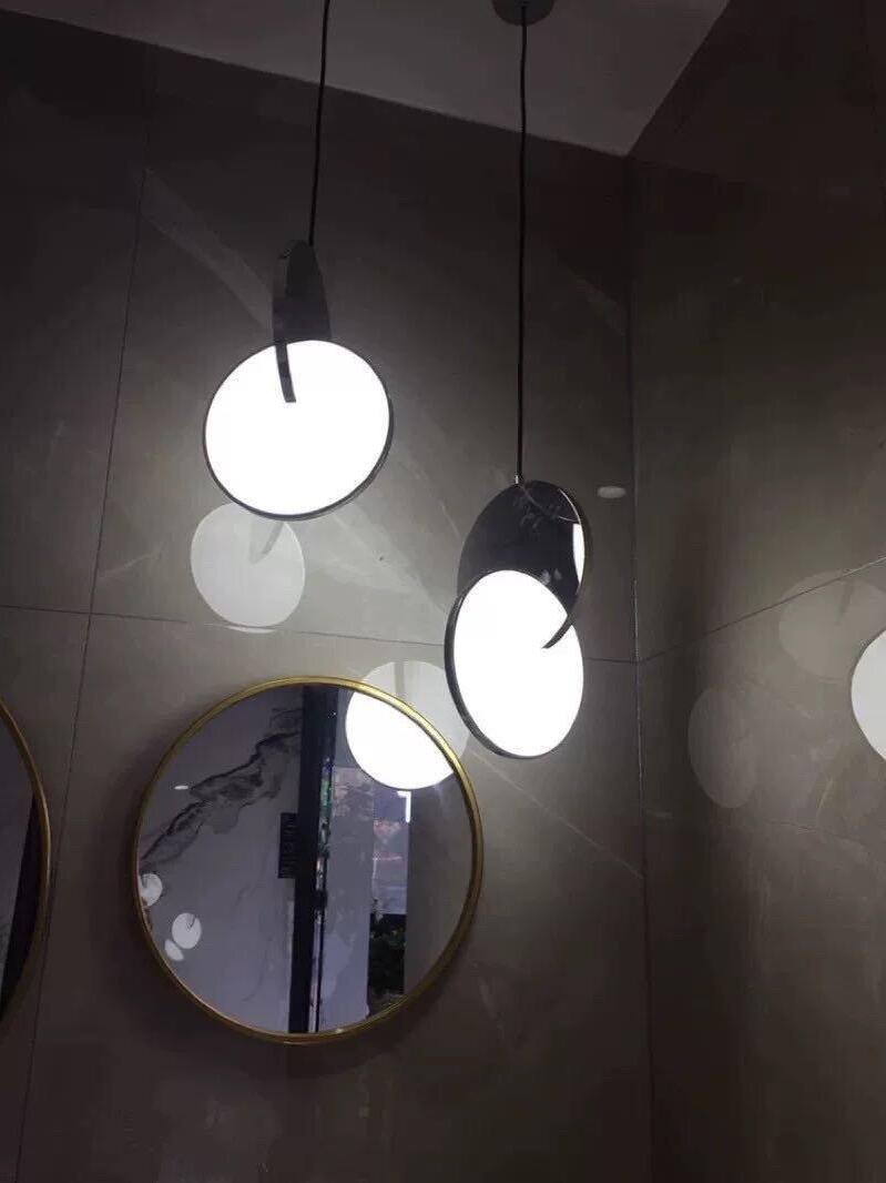 Reflective disc pendants and reflections near round gold-framed mirrors