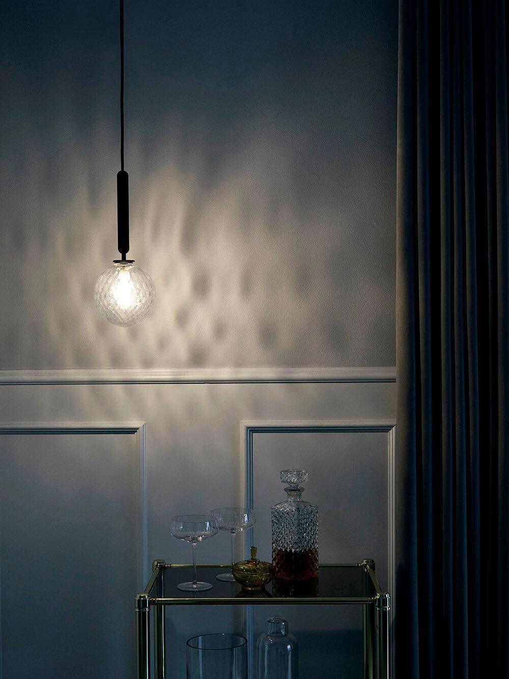 Textured clear globe casting a pattern on a dark wall