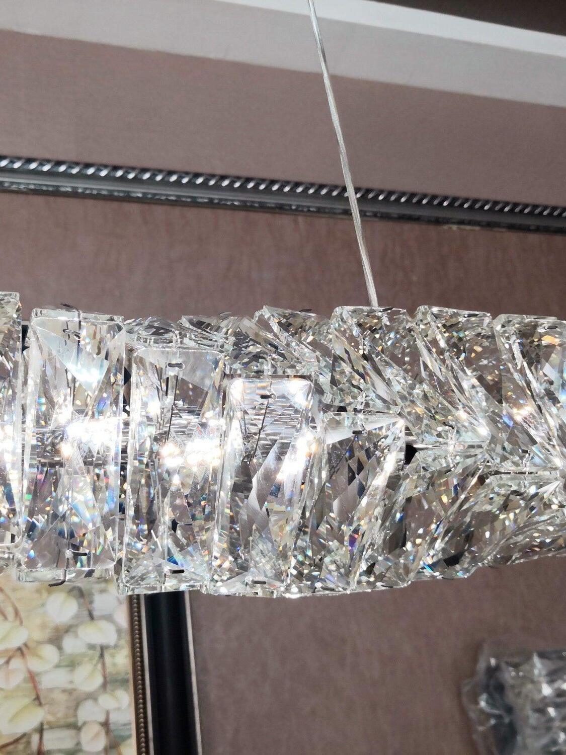 Close view of unlit crystal pieces and a suspension wire beside a textured wall and ceiling track