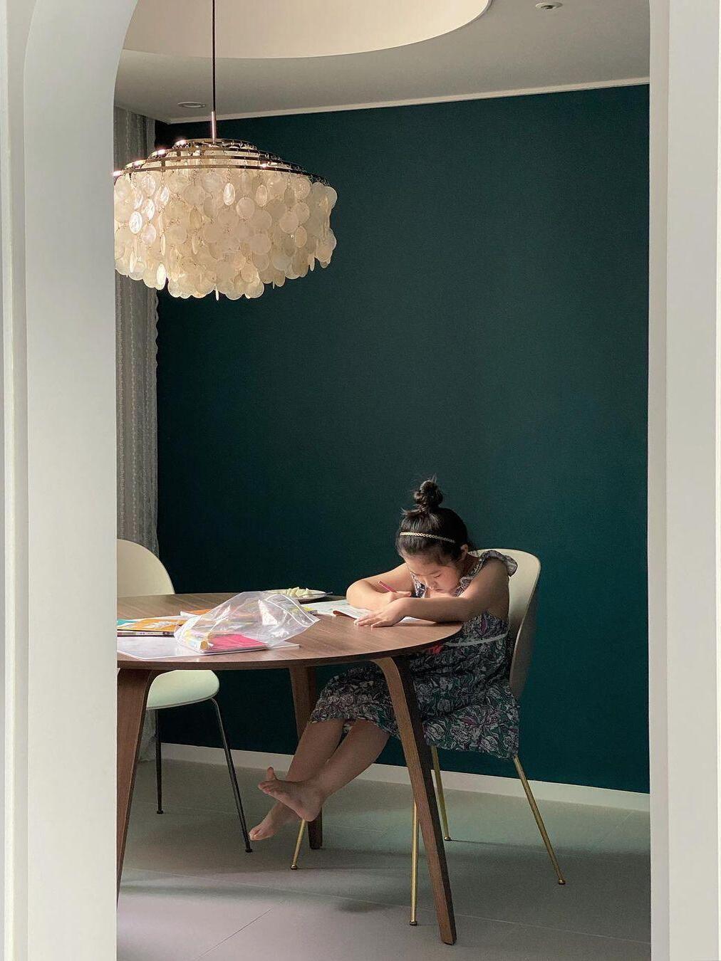 Round shell fixture beside a green dining-room wall