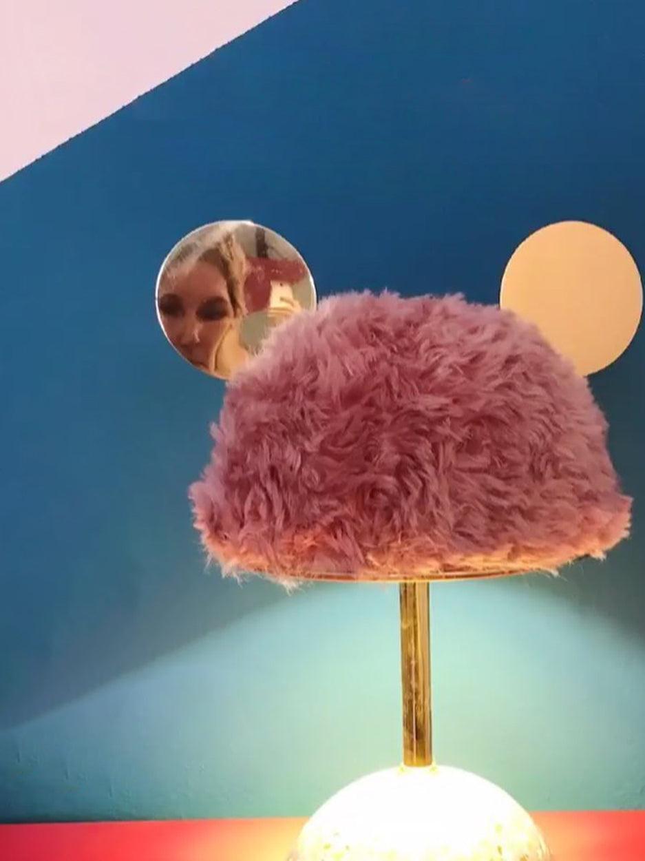 Closer pink plush shade and reflective discs against blue exhibition wall