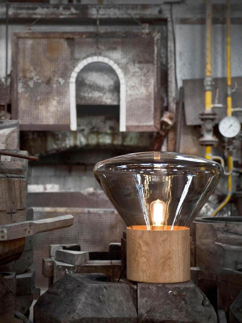 Lit smoky glass lamp on rough masonry platform in workshop setting