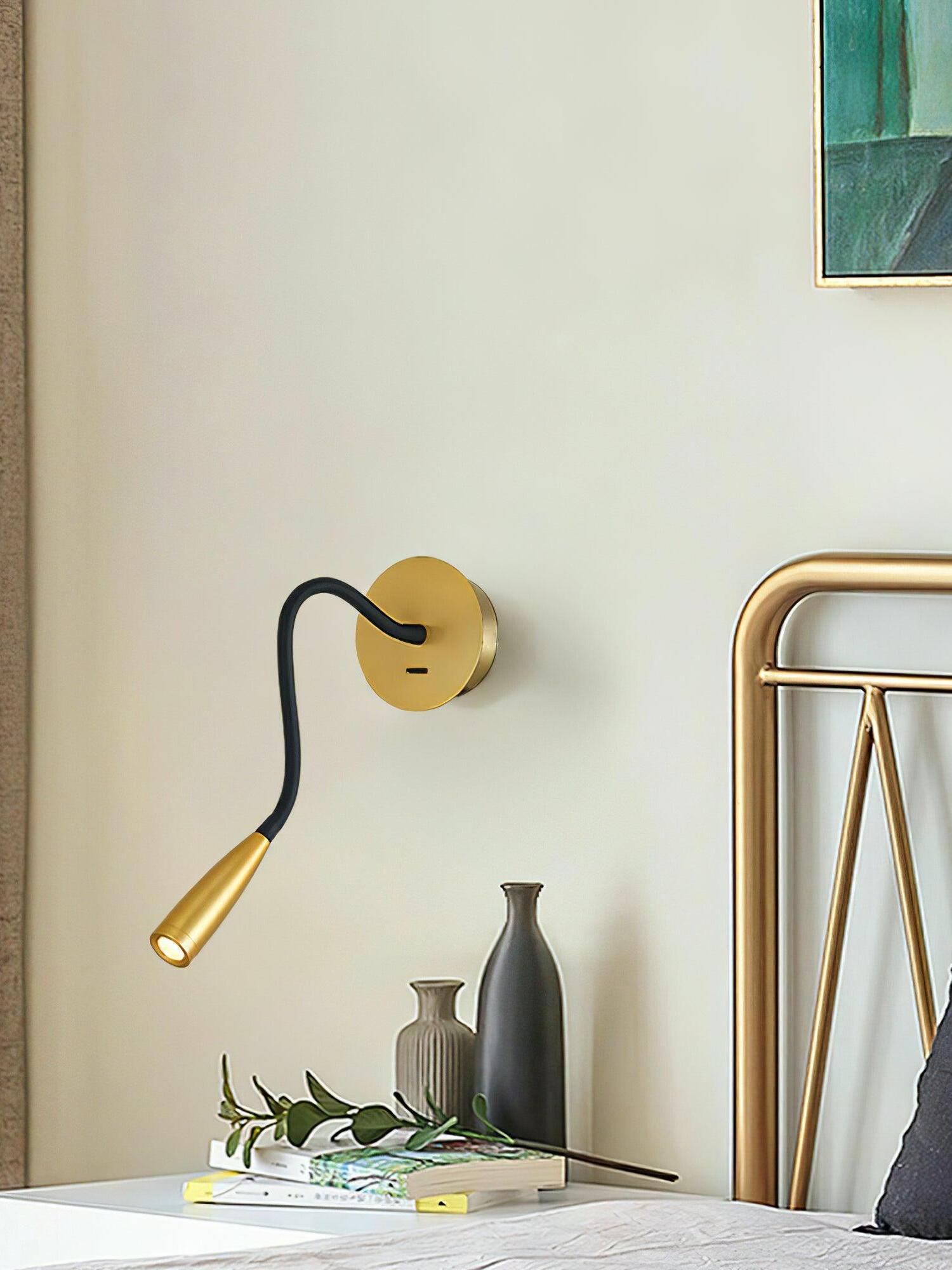 Gold Flexi beside a gold-toned bedframe above books and vases, showing the plate switch and angled illuminated head