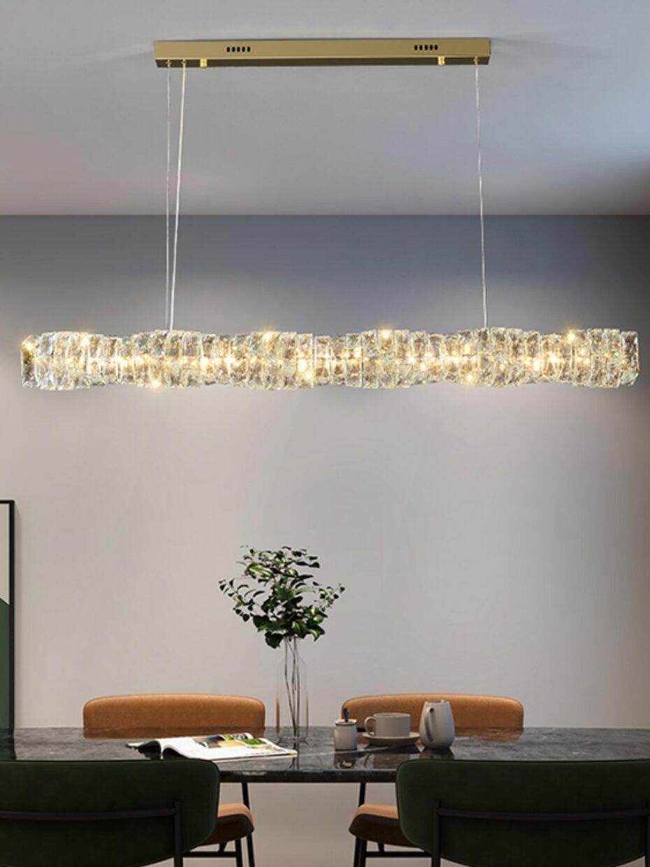 Gold rectangular canopy and illuminated crystal bar above a dark dining table with orange chairs