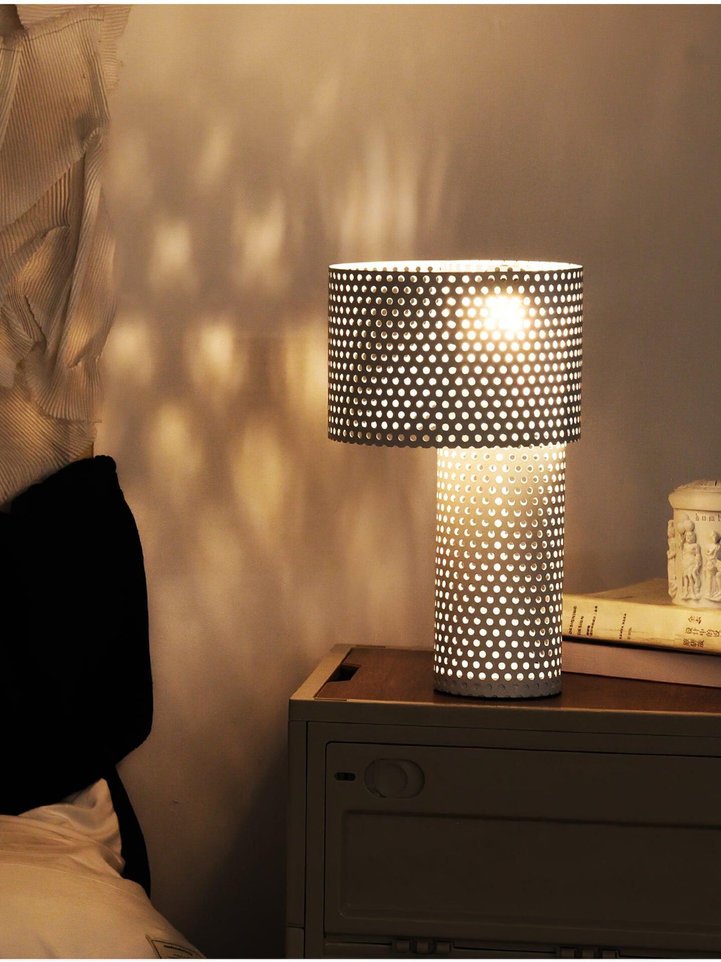 Lit white lamp on dark cabinet casting dots on wall