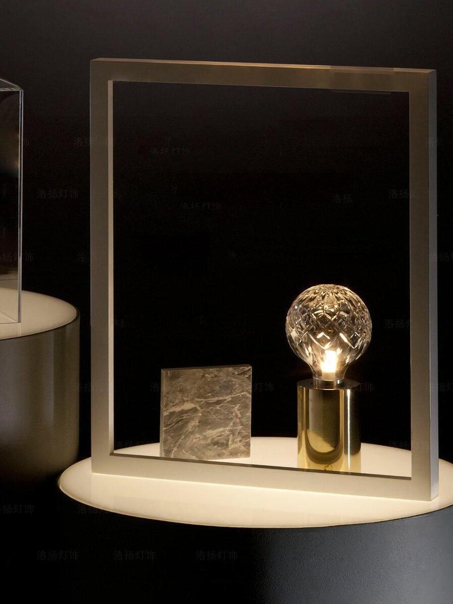 Lit glass-globe lamp beside ornament against dark panel