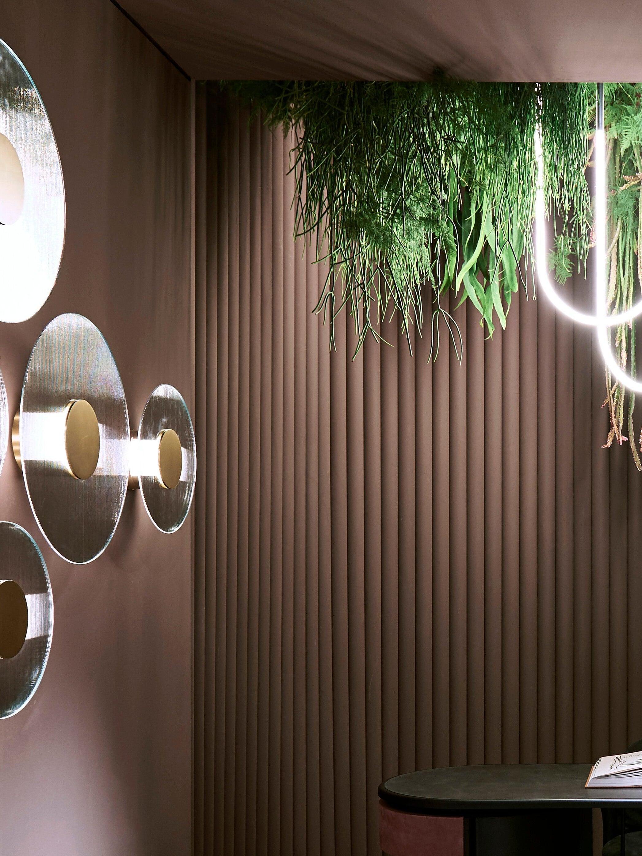 Round Button wall lights beside trailing greenery and wall ribs, with a separate glowing hanging loop at the right