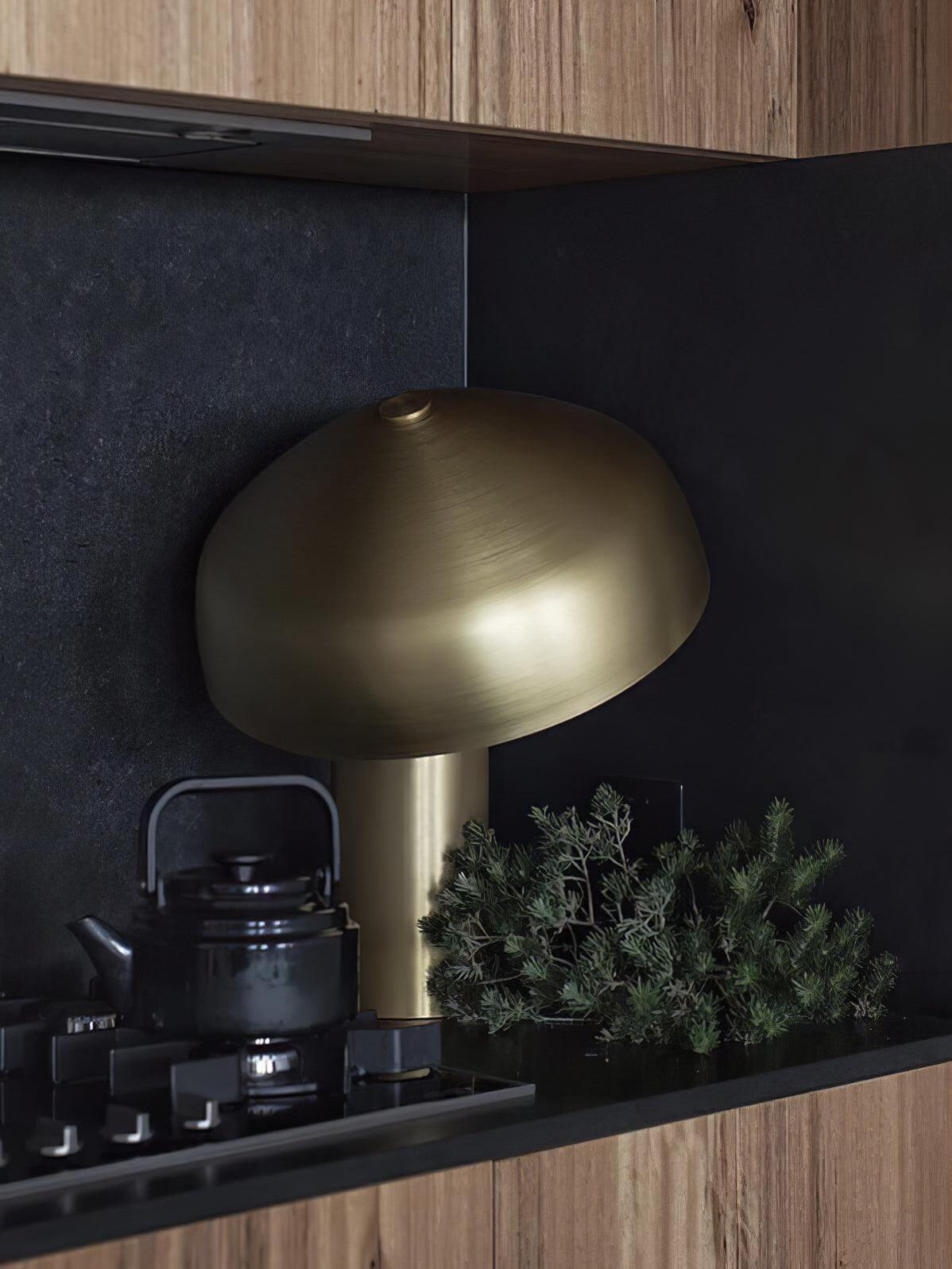 Gold dome lamp on dark shelf with foliage