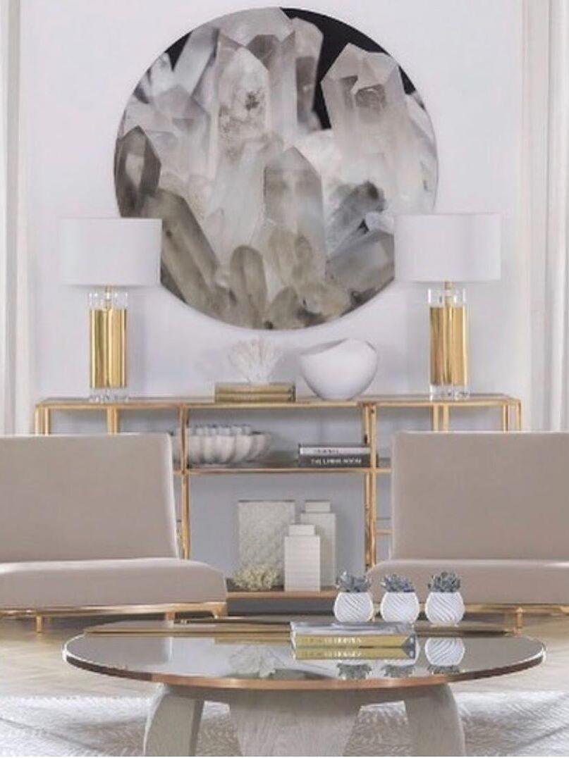 Two white-shade gold-tone lamps below round patterned artwork behind sofa
