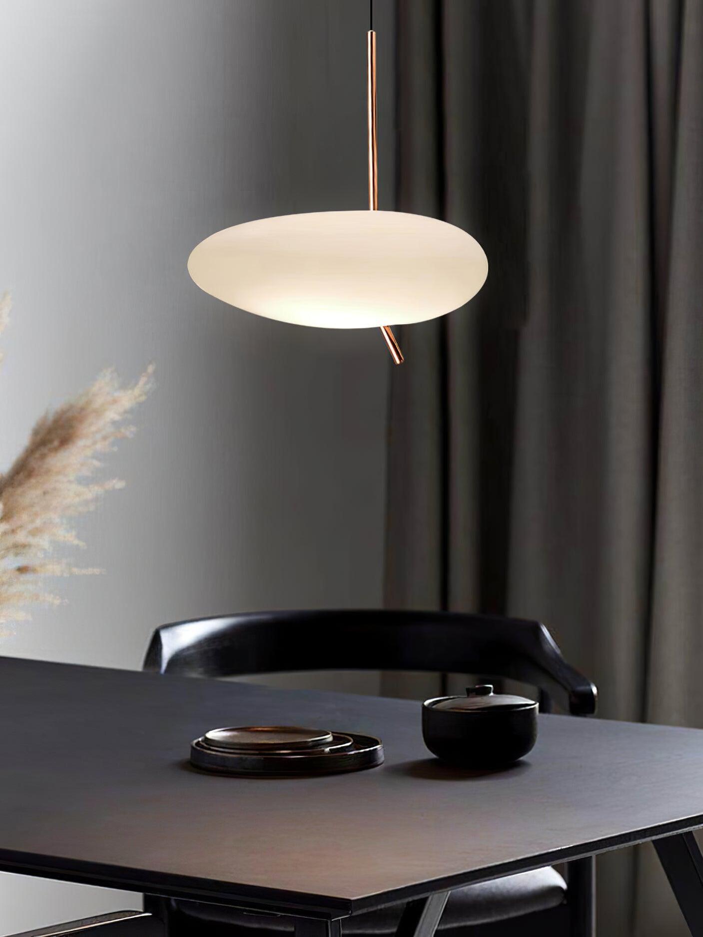 White pendant above a dark tabletop with a black telephone and chair