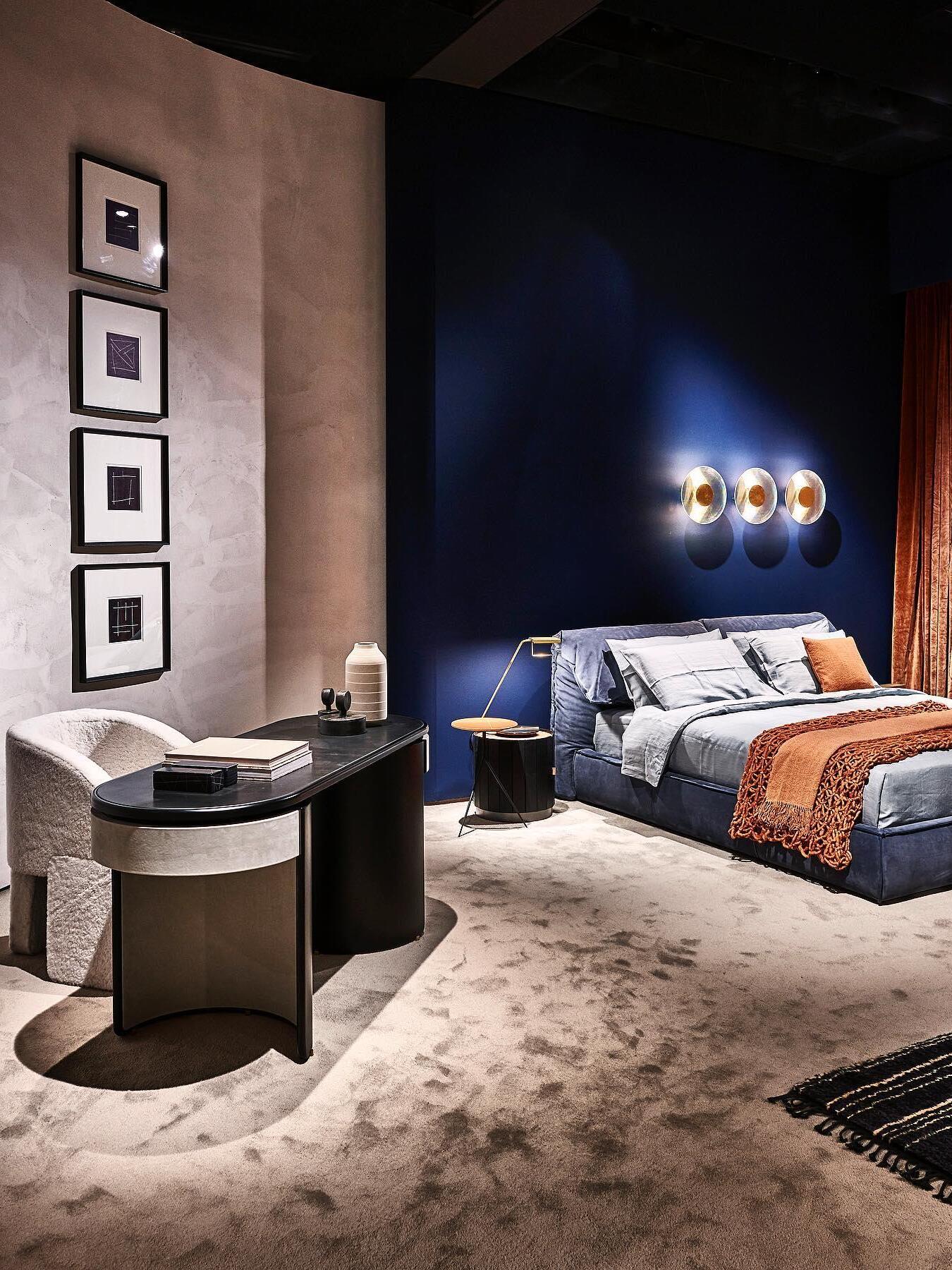 Wide blue-wall bedroom with three round Button lights, orange throw, rust curtains and a desk at the left