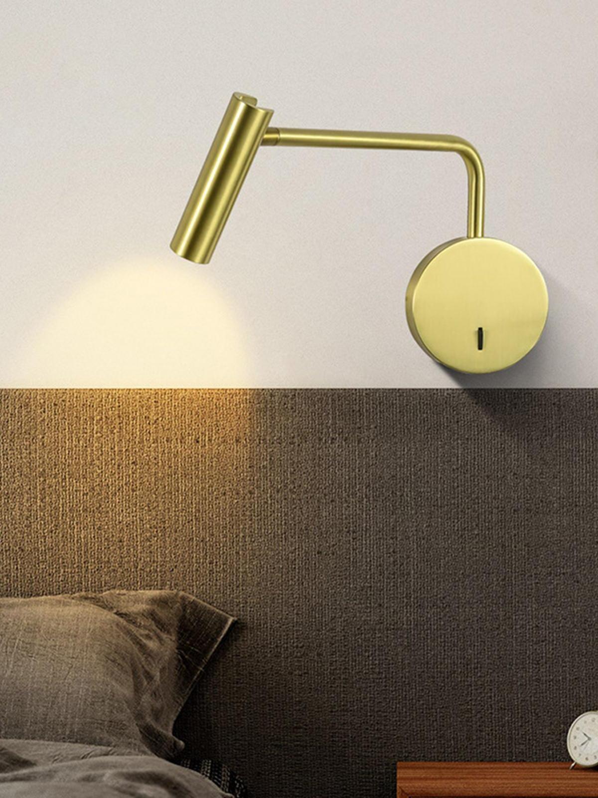 Gold-coloured reading light above a padded headboard