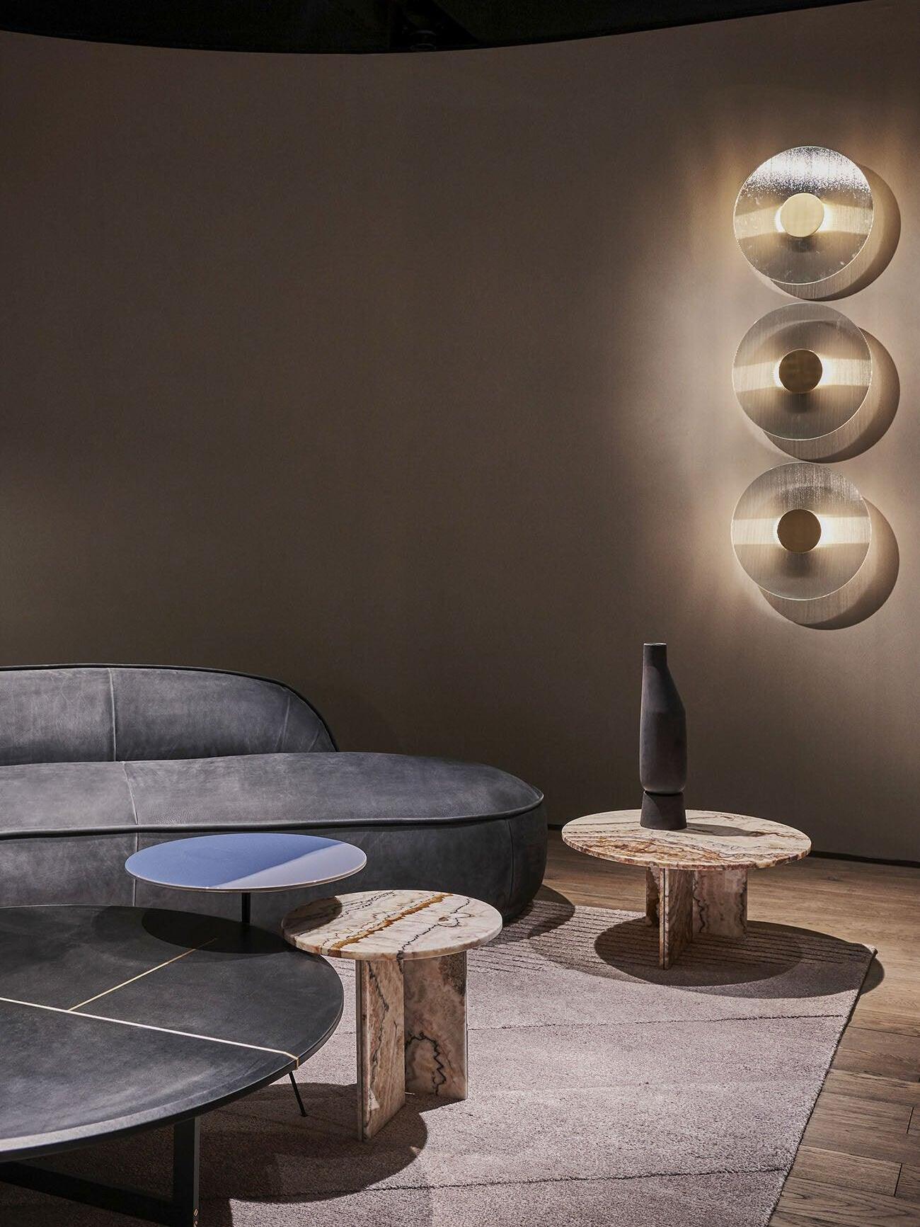 Wide seating view with three round Button wall lights, curved grey sofa, pale rug and round tables