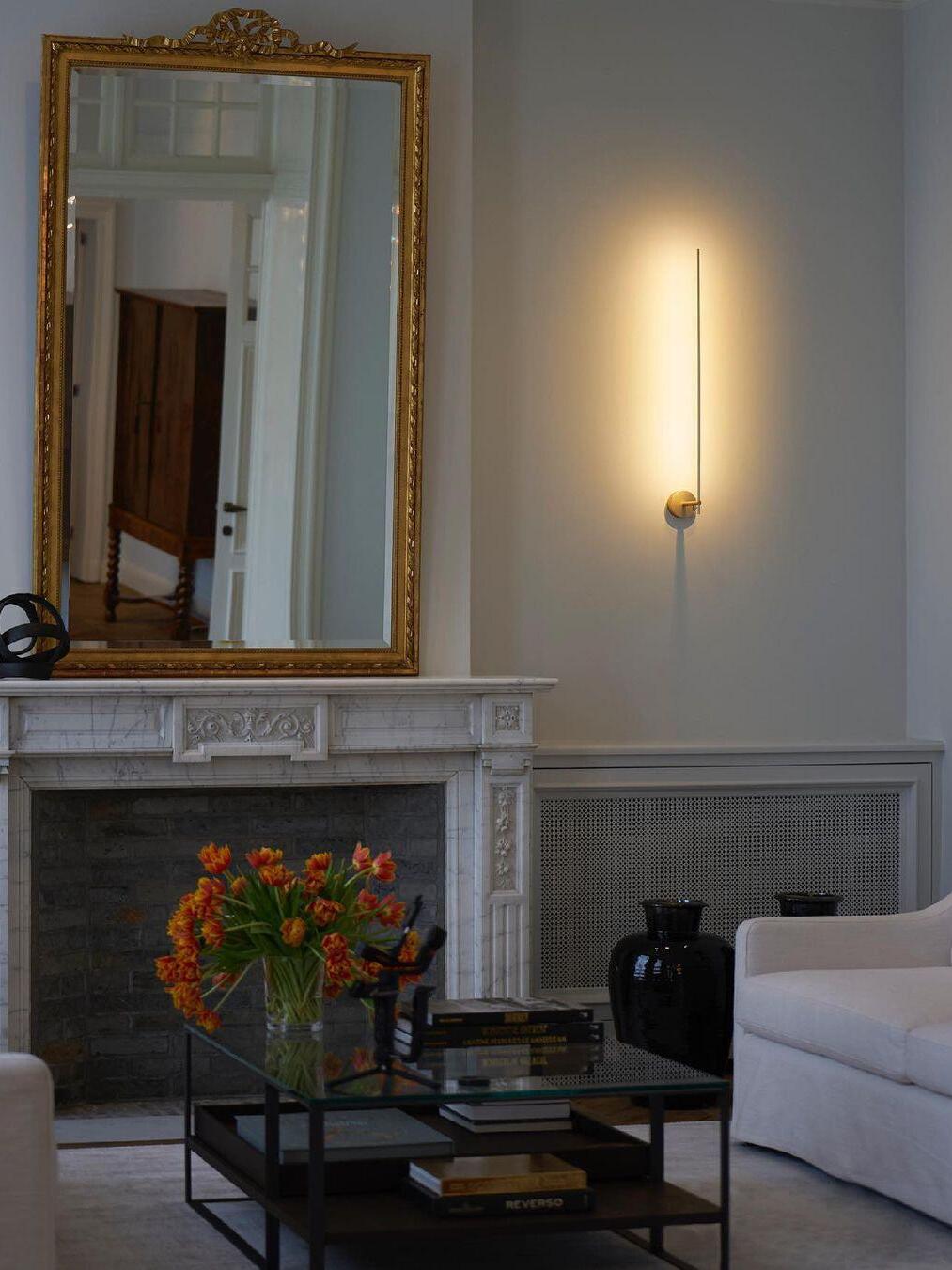 Slim wall light near a fireplace and mirror