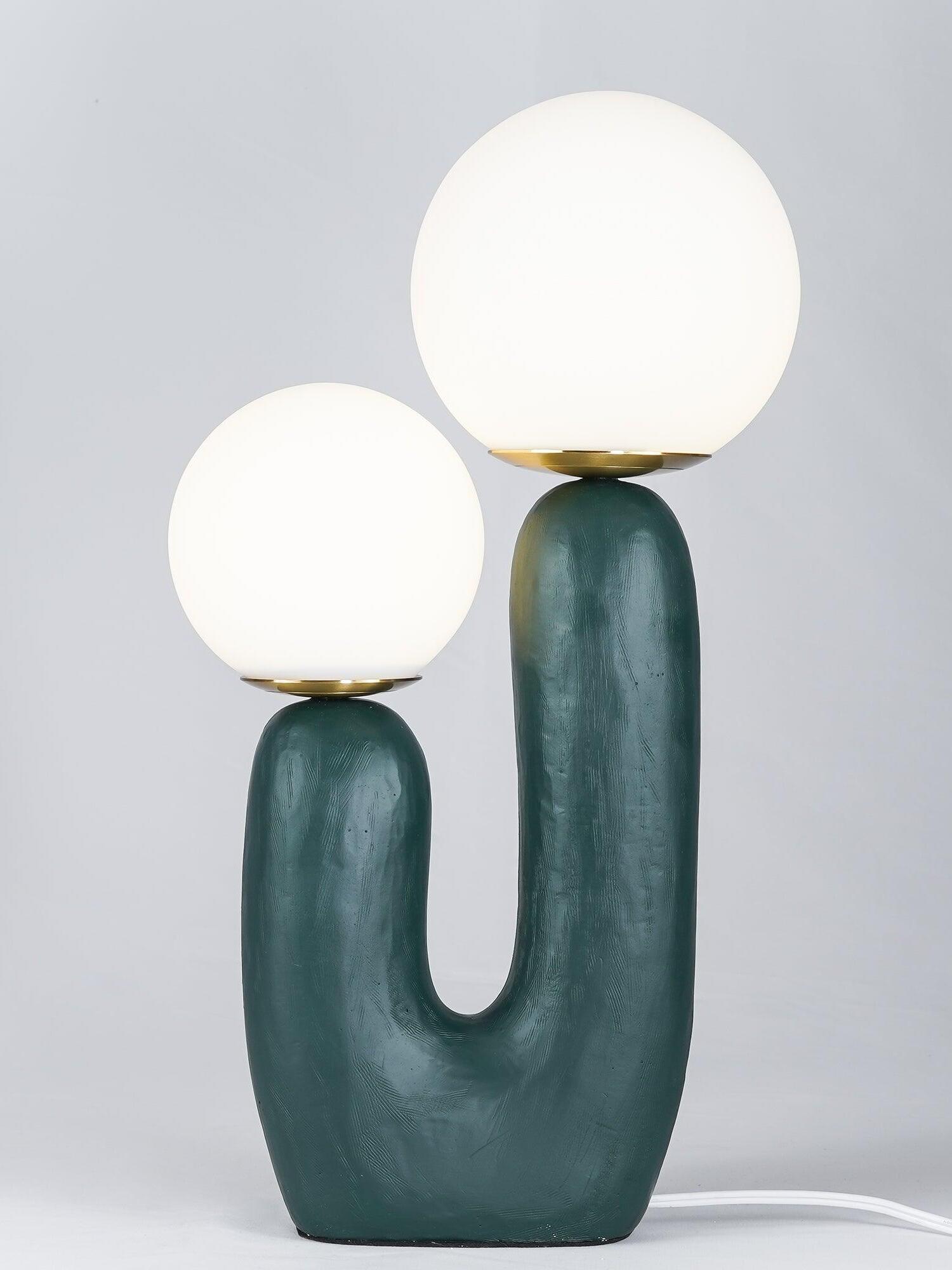 Green Oo Rough lamp against grey with brightly glowing globes, textured asymmetric body and metal collars