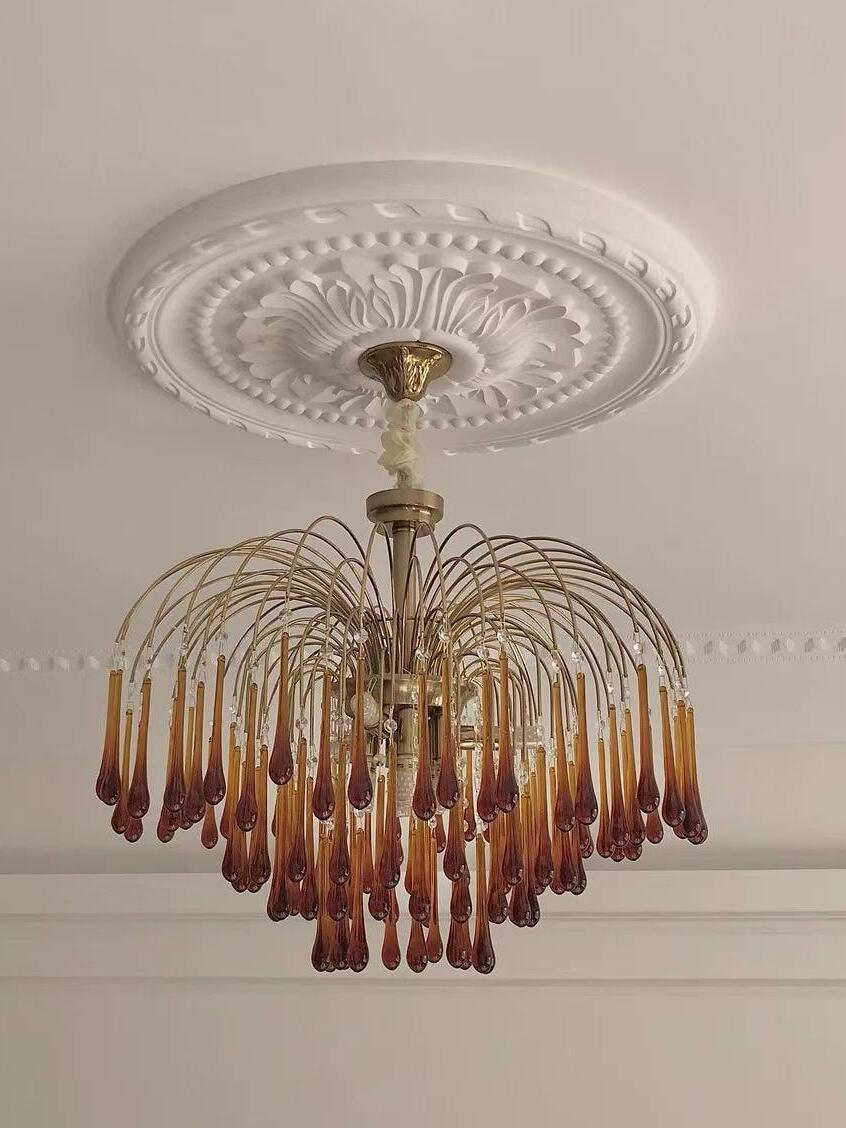 Wide chandelier beneath an ornate ceiling rose