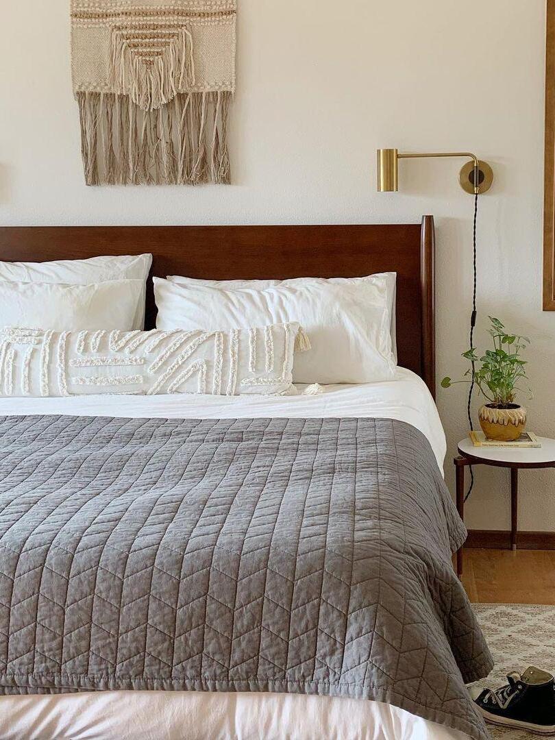 Brass-tone light beside wood headboard under textile wall art